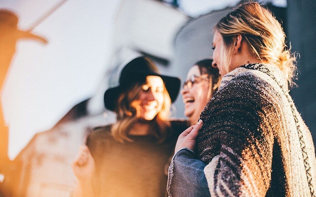 Drei Frauen stehen zusammen und lachen Drei Frauen stehen zusammen und lachen