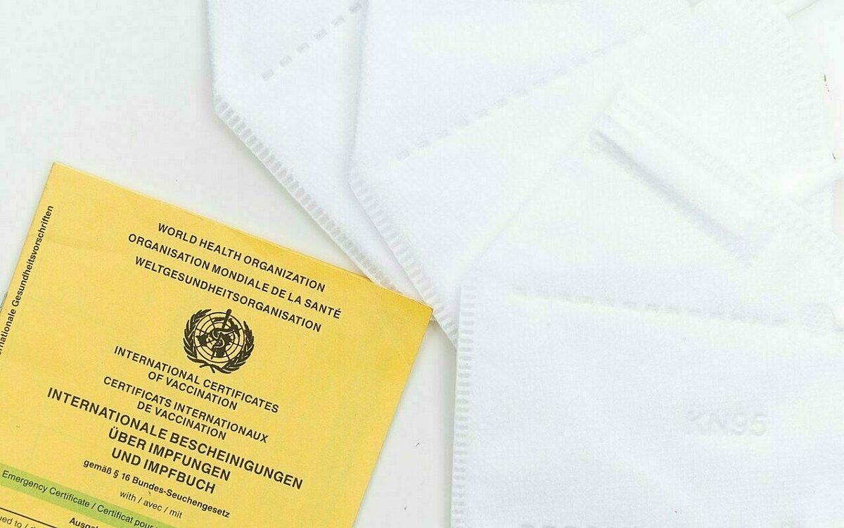 Ein Impfpass liegt neben mehreren FFP2 Masken Ein Impfpass liegt neben mehreren FFP2 Masken