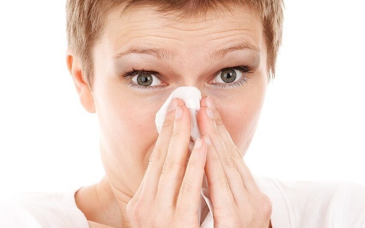 Eine Frau schnieft in ein Taschentuch Heuschnupfen Eine Frau schnieft in ein Taschentuch Heuschnupfen