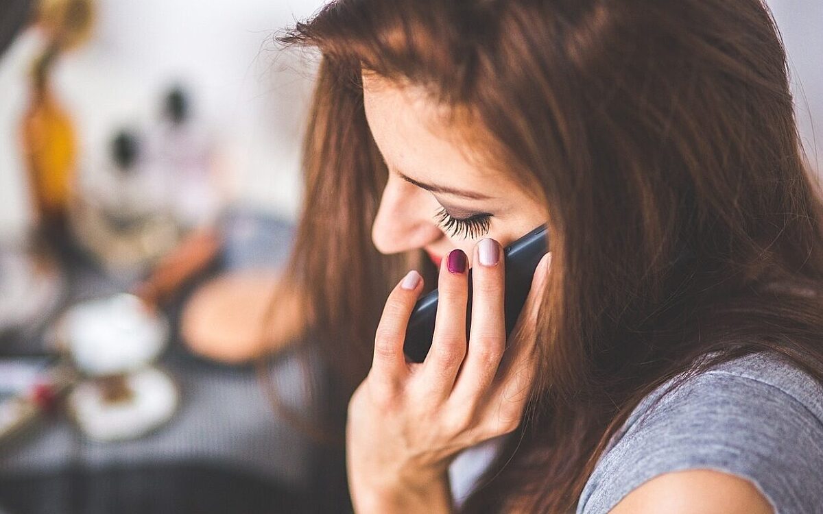 Eine junge Frau mit lackierten Fingernägeln telefoniert mit ihrem Handy Eine junge Frau mit lackierten Fingernägeln telefoniert mit ihrem Handy