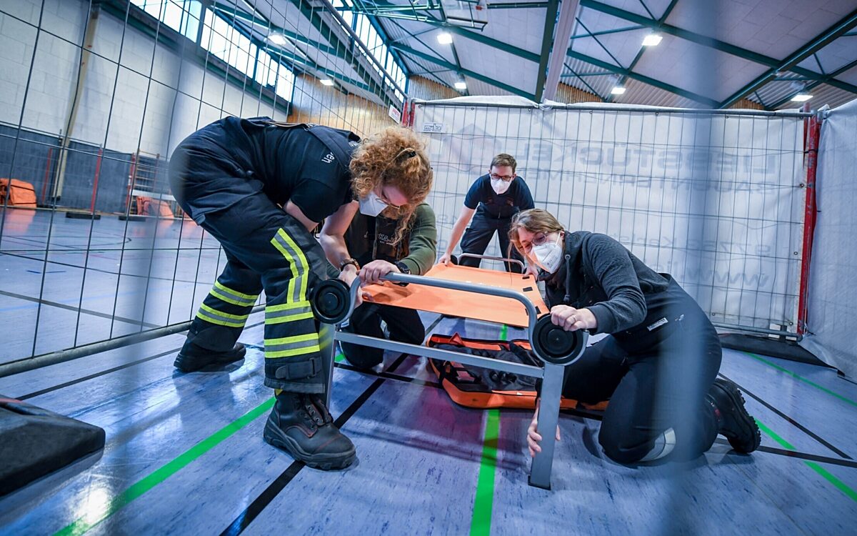 Freiwillige Helfer bauen eine Feldbett in der Main Spessart Halle auf Freiwillige Helfer bauen eine Feldbett in der Main Spessart Halle auf