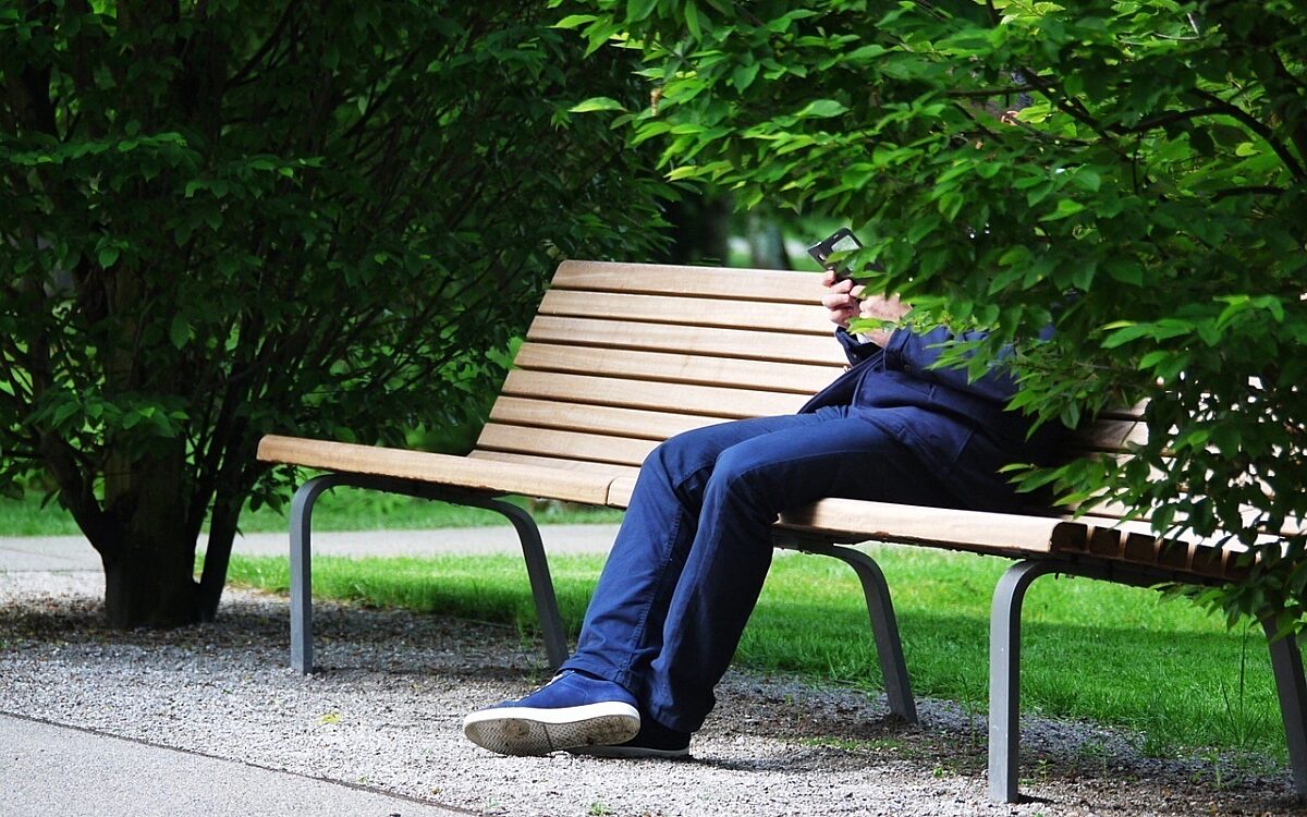 Mann sitzt auf einer Parkbank Mann sitzt auf einer Parkbank