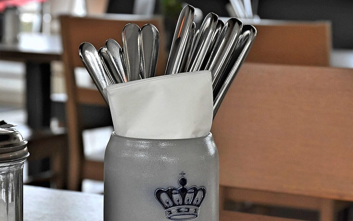 Messer und Gabeln in einem Bierkrug auf einem Tisch Messer und Gabeln in einem Bierkrug auf einem Tisch