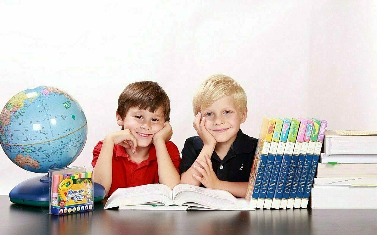 Schulkinder sitzen vor einem Buch Schulkinder sitzen vor einem Buch