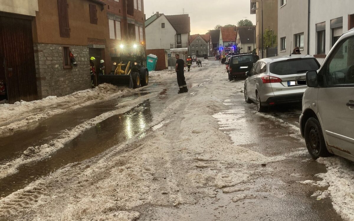In Birkenfeld räumt ein Radlader Hagelkörner von der Straße In Birkenfeld räumt ein Radlader Hagelkörner von der Straße
