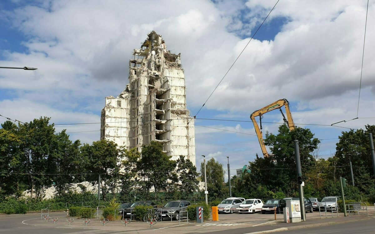 Ein großer Abrissbagger steht neben der Ruine des ehemaligen Hochhauses mit dem Dachcafe Ein großer Abrissbagger steht neben der Ruine des ehemaligen Hochhauses mit dem Dachcafe