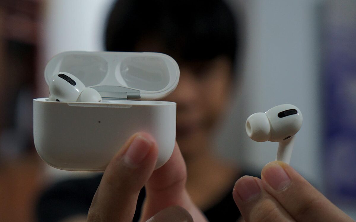 Eine Person hält Airpods in der Hand und hält sie in die Kamera Eine Person hält Airpods in der Hand und hält sie in die Kamera