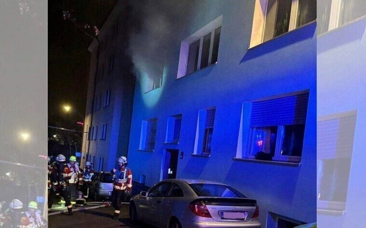 Feuerwehrkräfte vor einem Haus. Aus dem Fenster dringt Rauch Feuerwehrkräfte vor einem Haus. Aus dem Fenster dringt Rauch