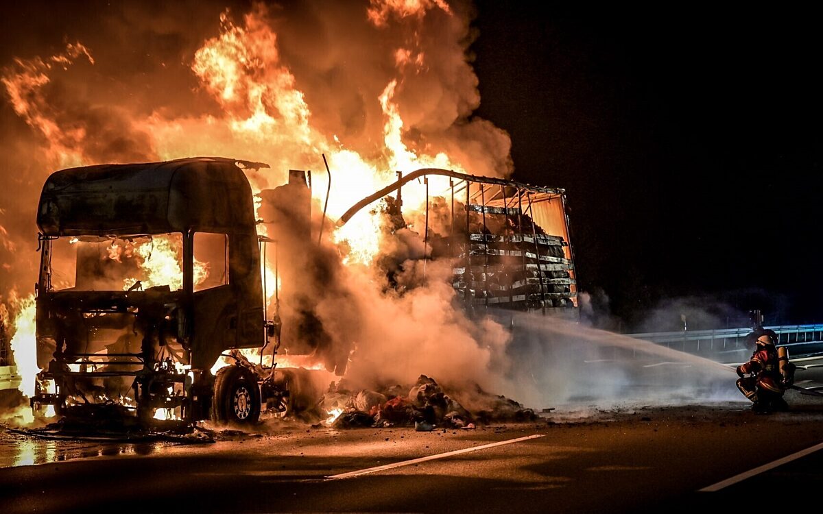 Ein Feuerwehrmann löscht die Flammen des LKW Ein Feuerwehrmann löscht die Flammen des LKW