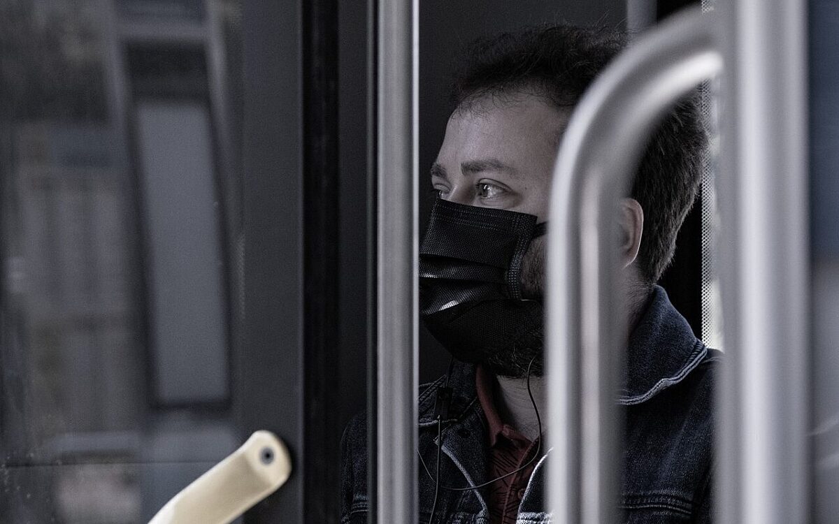 Ein Mann sitzt in einem Bus und trägt eine Maske Ein Mann sitzt in einem Bus und trägt eine Maske