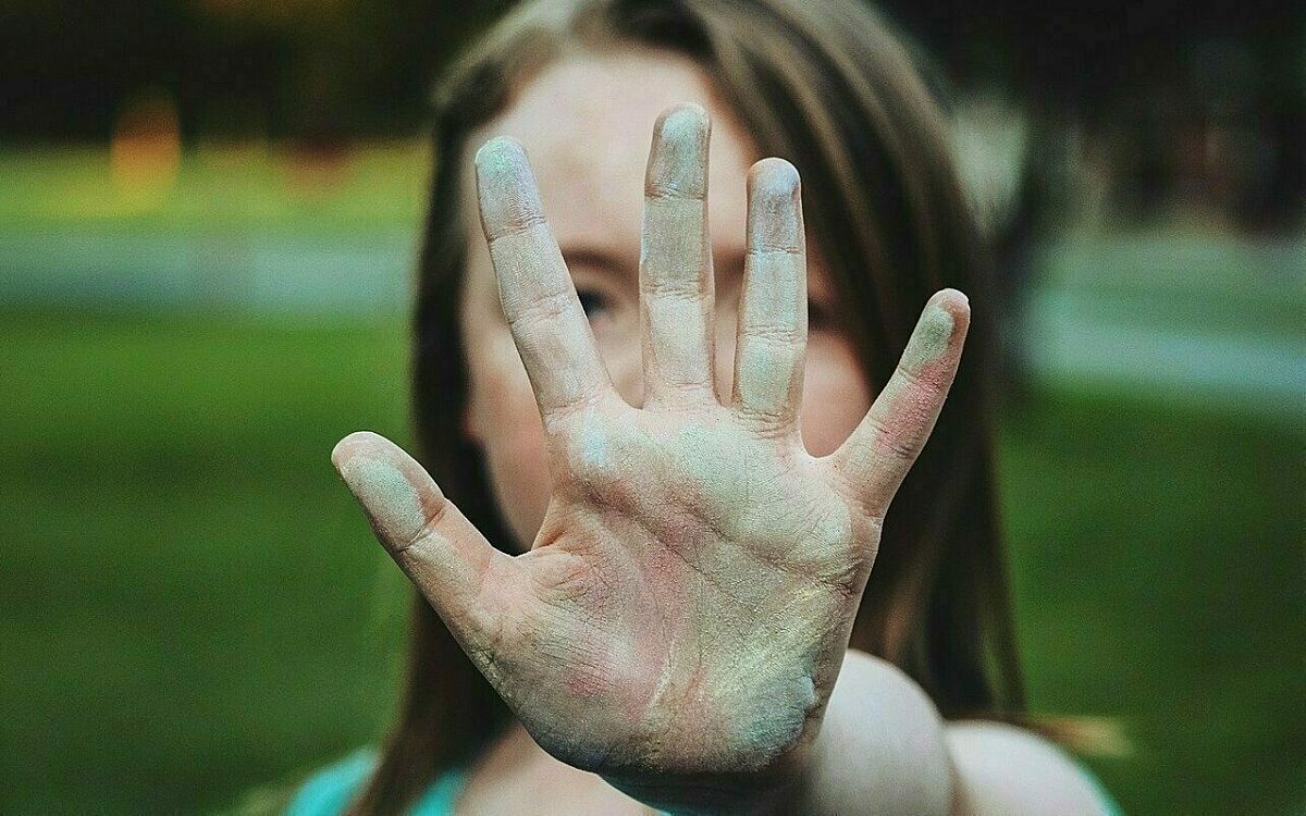 Ein Mädchen hält abwehrend die Hand vor ihr Gesicht Ein Mädchen hält abwehrend die Hand vor ihr Gesicht