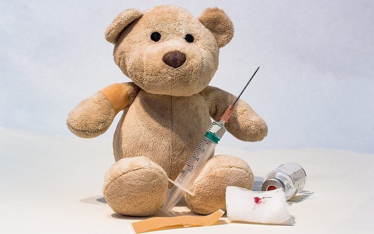 Ein Teddy nach einer Impfung mit einem Pflaster am Arm Ein Teddy nach einer Impfung mit einem Pflaster am Arm