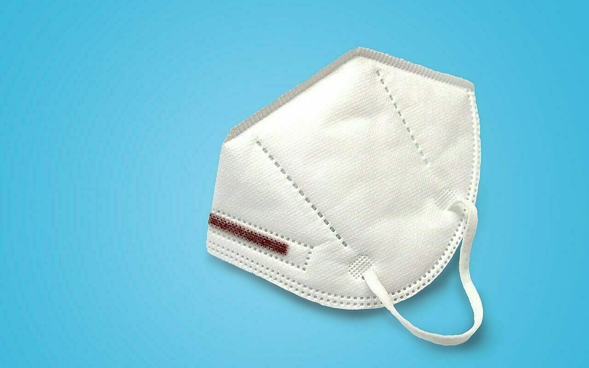 Eine FFP2-Maske vor einem blauen Hintergrund Eine FFP2-Maske vor einem blauen Hintergrund