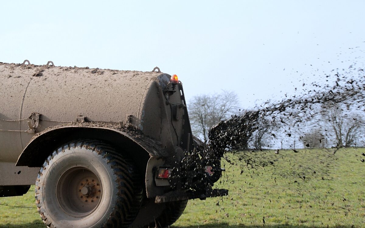Ein Traktor bringt Gülle auf ein Feld aus Ein Traktor bringt Gülle auf ein Feld aus