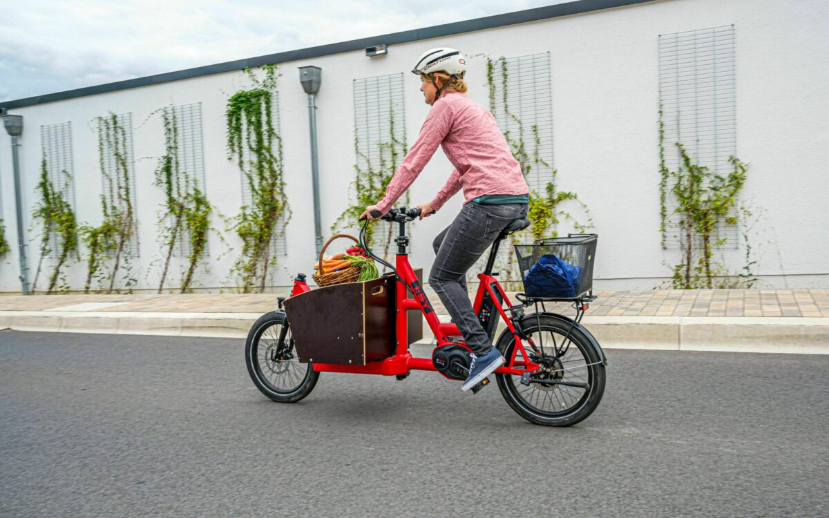 Eine Frau fährt mit einem beladenen Lastenrad Eine Frau fährt mit einem beladenen Lastenrad