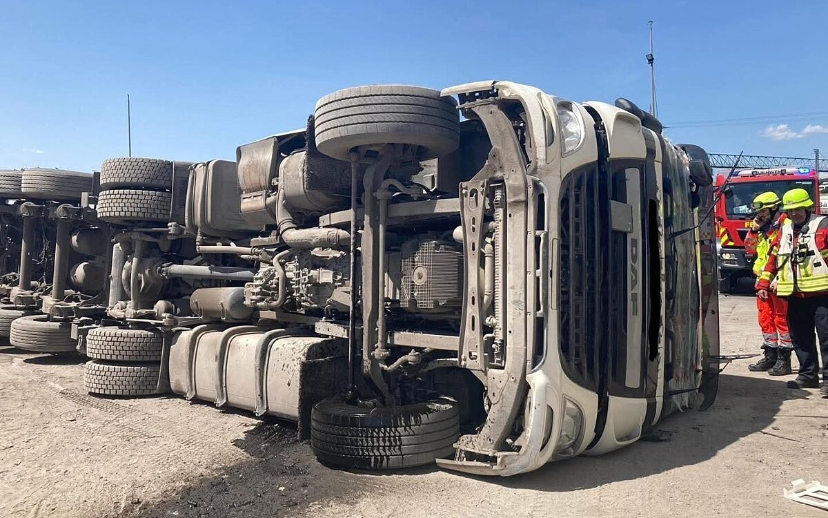 Der umgestürzte Laster liegt auf einem Firmengelände auf der Seite Der umgestürzte Laster liegt auf einem Firmengelände auf der Seite