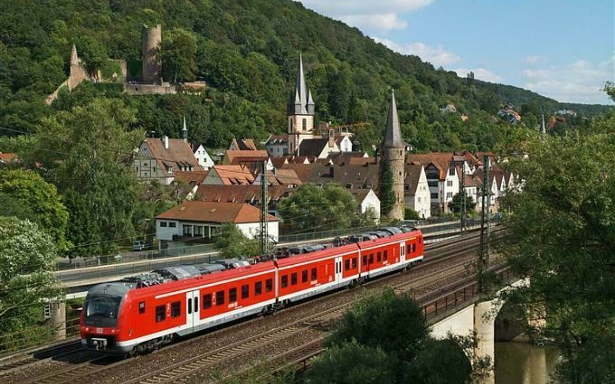 Die rote Mainfrankenbahn fährt und im Hintergrund ist die Stadt Gemünden zu sehen Die rote Mainfrankenbahn fährt und im Hintergrund ist die Stadt Gemünden zu sehen