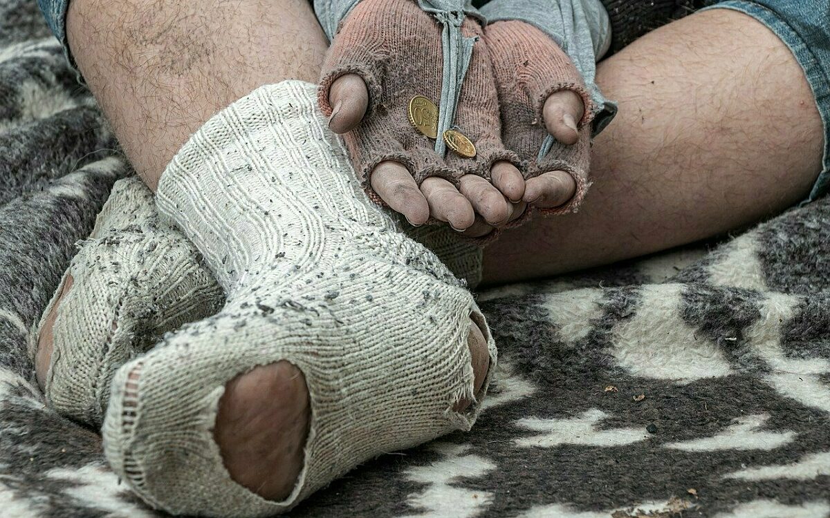 Ein obdachloser Mensch bettelt auf einer Decke Ein obdachloser Mensch bettelt auf einer Decke