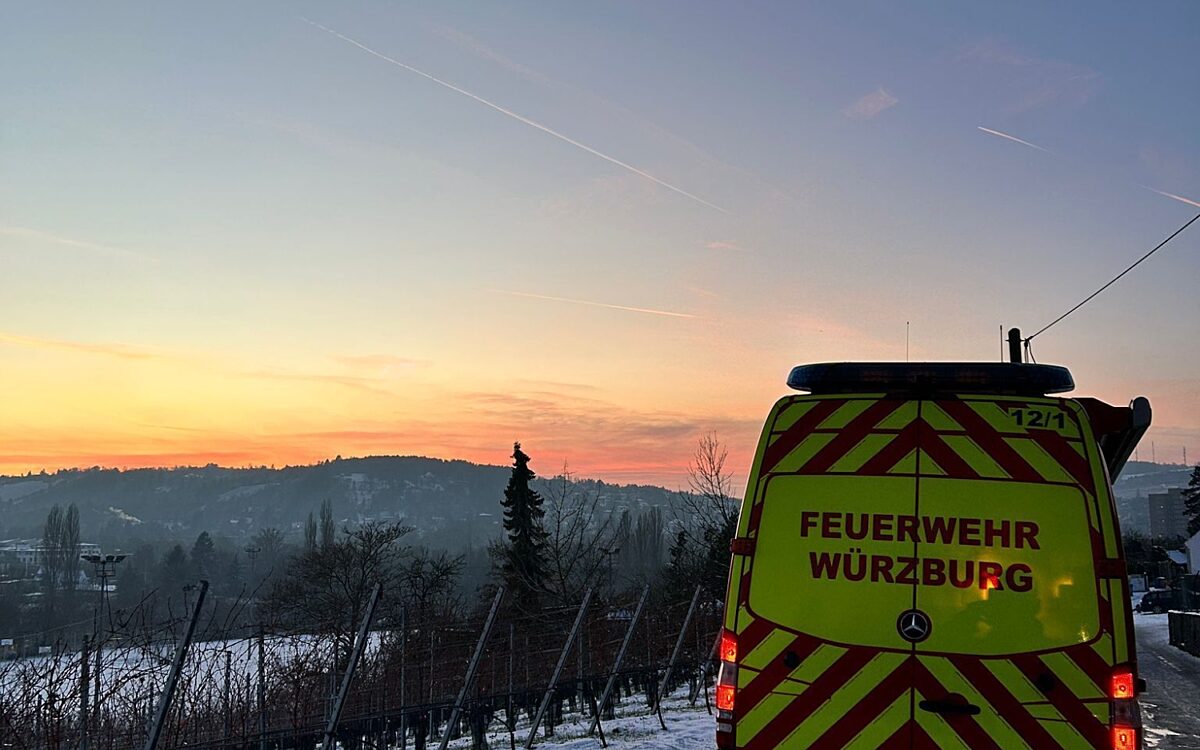 Ein Feuerwehrautos steht auf einem verschneiten Weinbergweg. Im Hintergrund geht die Sonne unter Ein Feuerwehrautos steht auf einem verschneiten Weinbergweg. Im Hintergrund geht die Sonne unter