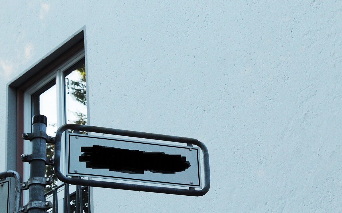 Der Name eines Straßenschildes ist schwarz übermalt Der Name eines Straßenschildes ist schwarz übermalt