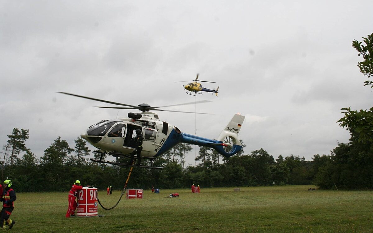 Hubschrauber schweben im Rahmen einer Löschübung über einer Wiese Hubschrauber schweben im Rahmen einer Löschübung über einer Wiese