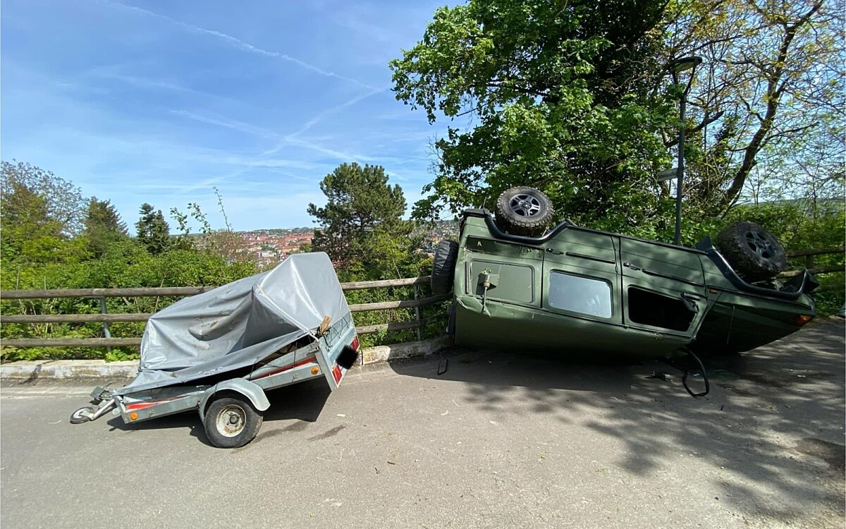 Der Geländewagen liegt auf dem Dach neben einem Anhänger Der Geländewagen liegt auf dem Dach neben einem Anhänger
