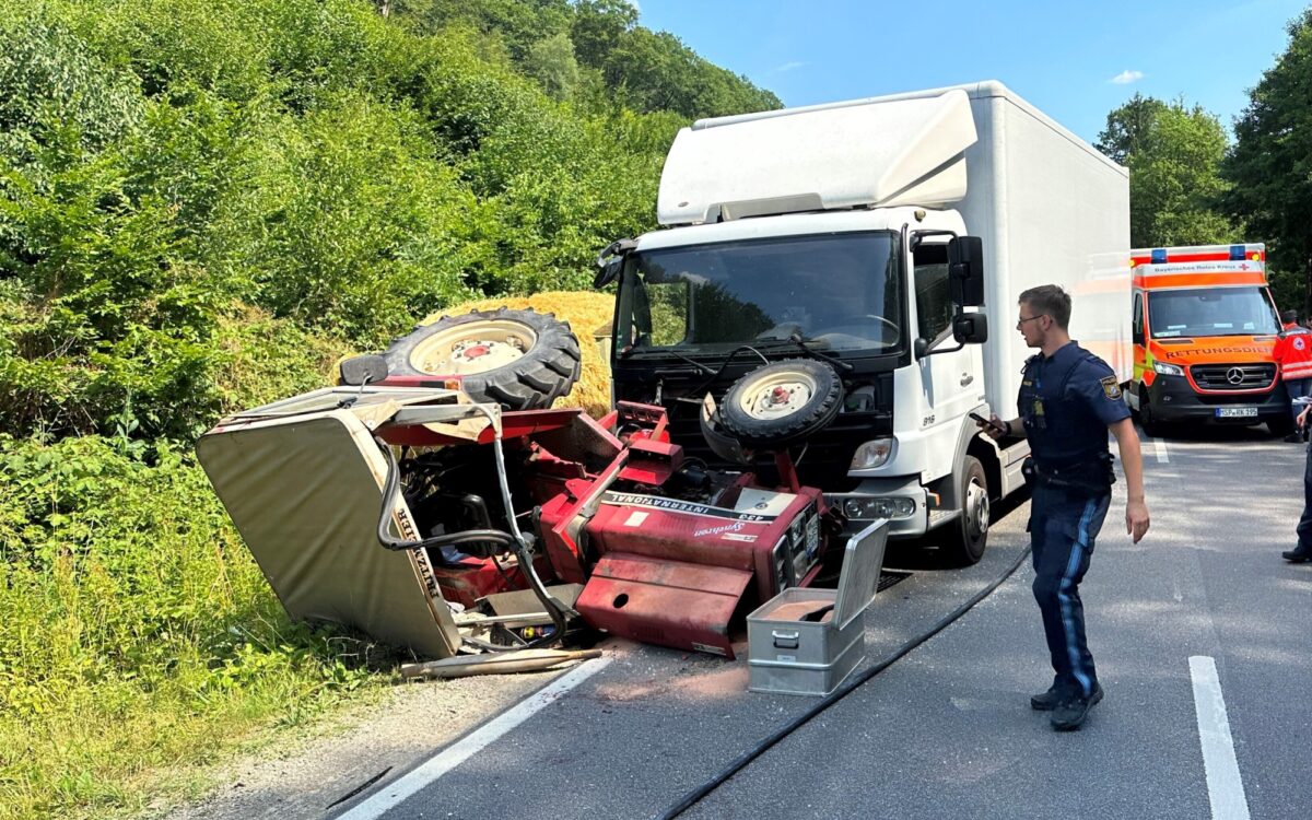 Ein Traktor liegt zerstört auf der Seite, hinter ihm steht ein LKW Ein Traktor liegt zerstört auf der Seite, hinter ihm steht ein LKW